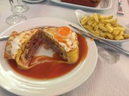 Francesinha - sandwich with smoked sausage, garlic beef, other meat (idk man), with melted cheese and fried egg, served in beer sauce. I ate half and tapped out.